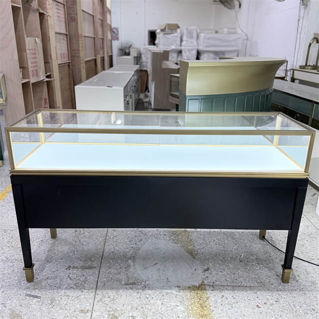 Wide-body glass-top jewelry display counter with brass frame, white LED-illuminated interior, and matte black base — custom by Shangyuan Display